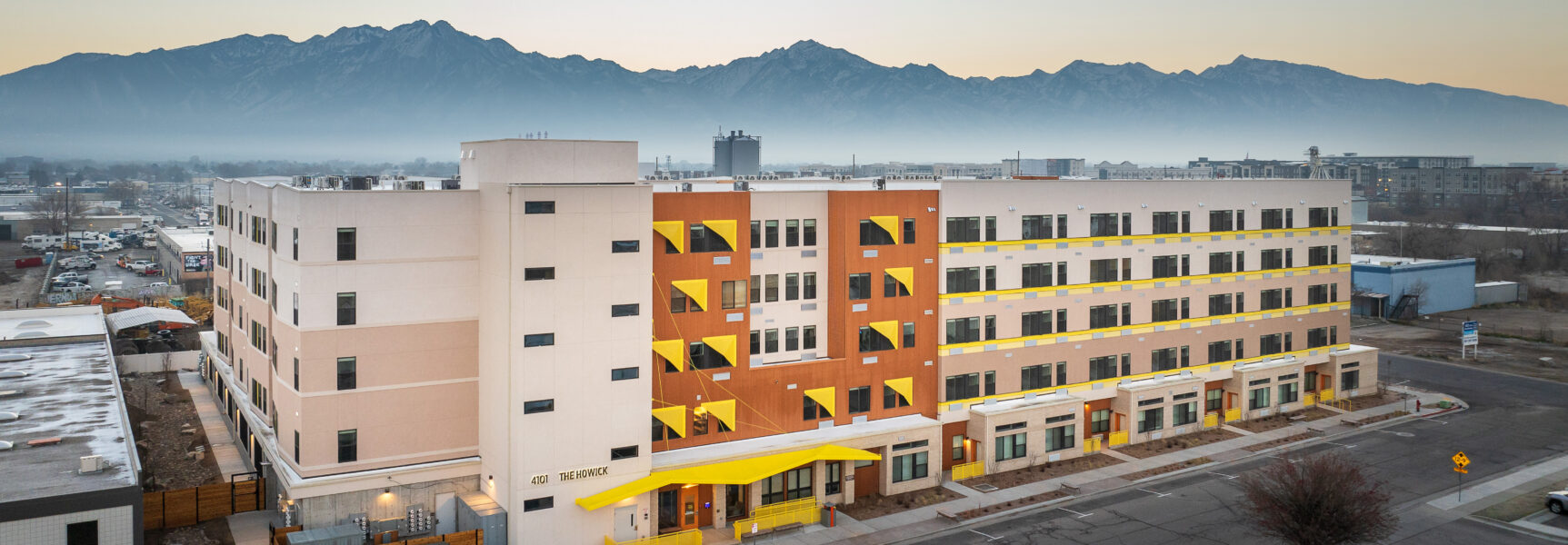 Large modern building with mountain backdrop, labeled "The Howick" on facade.
