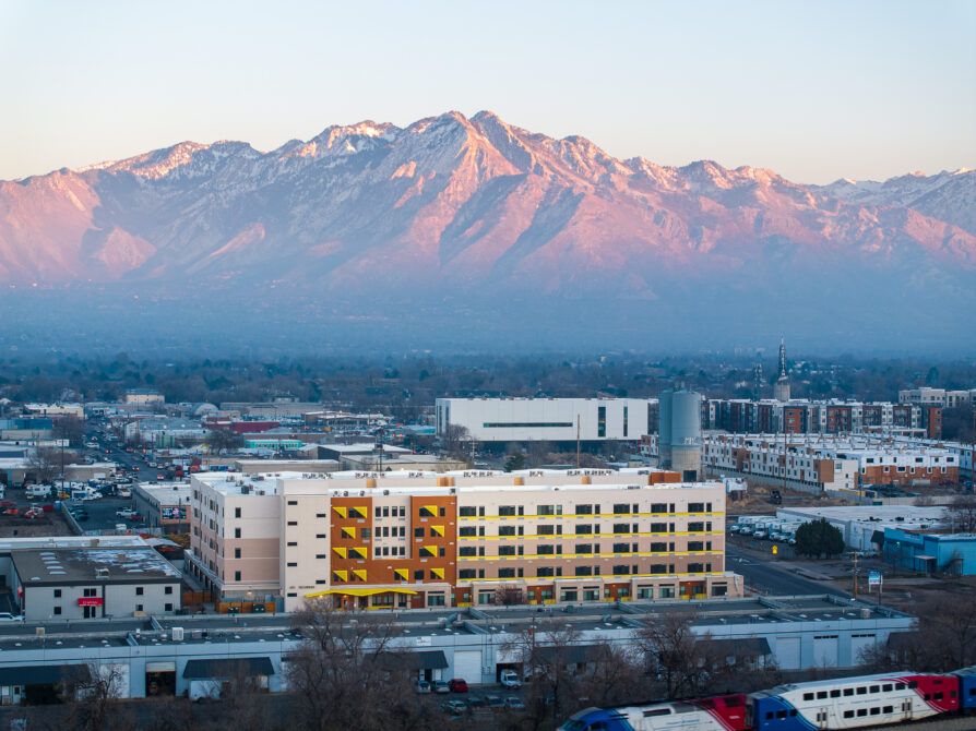 Urban landscape with large mountains in the background at sunset.